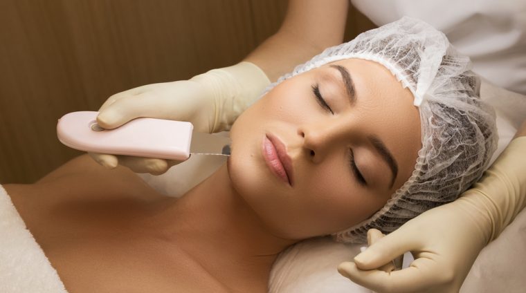Beautiful woman in professional beauty spa salon during ultrasonic facial cleansing procedure